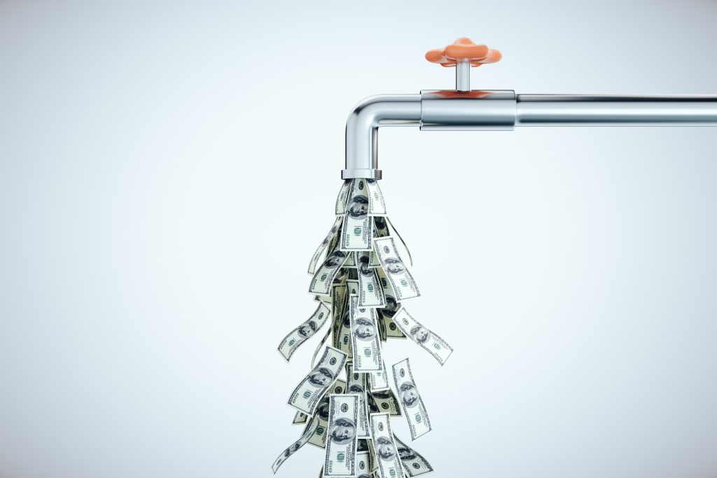 Water tap dripping dollar bills on a gray background. Business and financial success concept to illustrate cash flow.